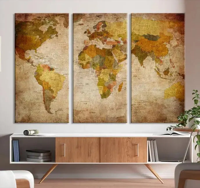 The Old Antique World Map Wall Art Canvas Print, featuring a three-panel vintage design and crafted with museum-quality canvas and UV-protective coating, hangs elegantly against a dark wall.