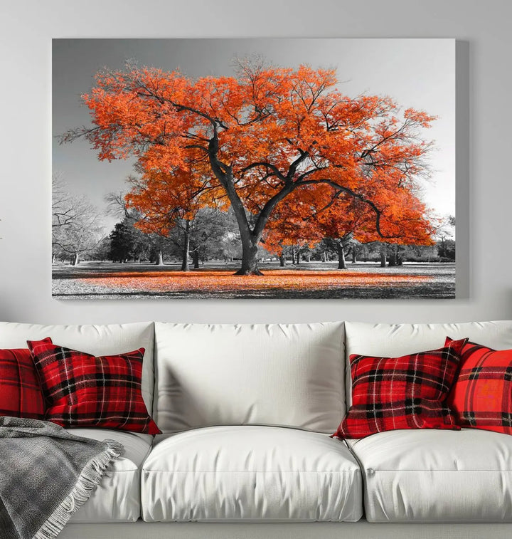 The "Orange Autumn Tree Canvas Wall Art Print" features a triptych of a tree with vibrant orange leaves set in a grayscale park. It's printed on museum-quality canvas and safeguarded by a UV-protective coating, making it the perfect artwork for any space.