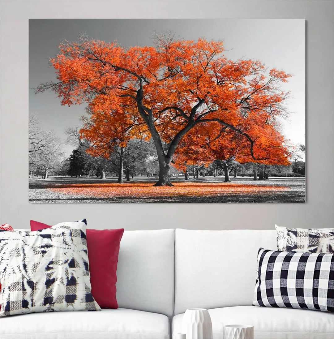 The "Orange Autumn Tree Canvas Wall Art Print" features a triptych of a tree with vibrant orange leaves set in a grayscale park. It's printed on museum-quality canvas and safeguarded by a UV-protective coating, making it the perfect artwork for any space.