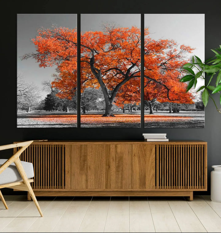 The "Orange Autumn Tree Canvas Wall Art Print" features a triptych of a tree with vibrant orange leaves set in a grayscale park. It's printed on museum-quality canvas and safeguarded by a UV-protective coating, making it the perfect artwork for any space.