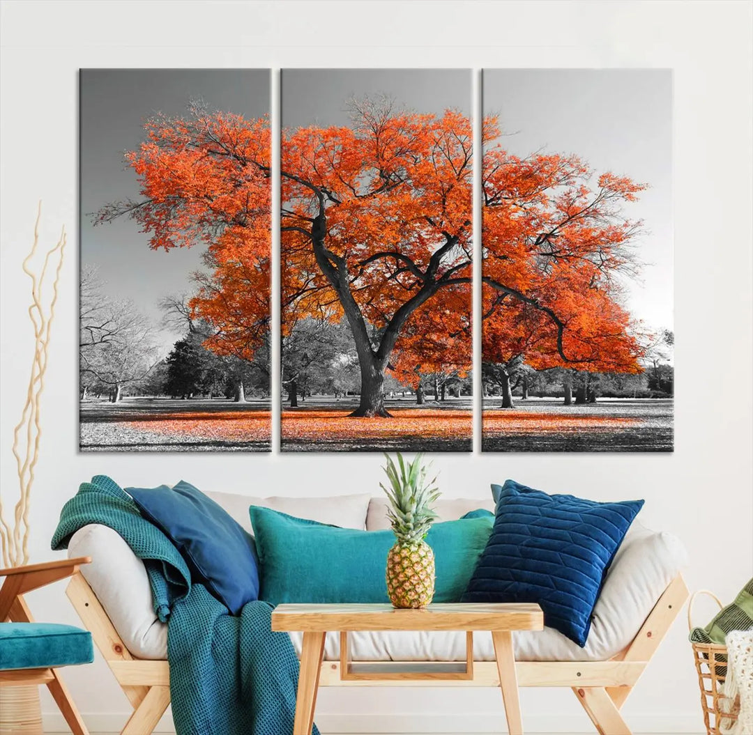 The "Orange Autumn Tree Canvas Wall Art Print" features a triptych of a tree with vibrant orange leaves set in a grayscale park. It's printed on museum-quality canvas and safeguarded by a UV-protective coating, making it the perfect artwork for any space.