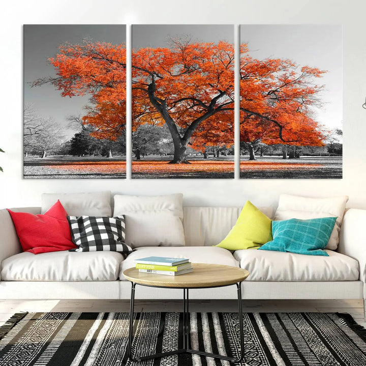 The "Orange Autumn Tree Canvas Wall Art Print" features a triptych of a tree with vibrant orange leaves set in a grayscale park. It's printed on museum-quality canvas and safeguarded by a UV-protective coating, making it the perfect artwork for any space.