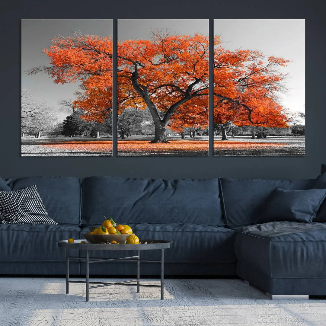 The "Orange Autumn Tree Canvas Wall Art Print" features a triptych of a tree with vibrant orange leaves set in a grayscale park. It's printed on museum-quality canvas and safeguarded by a UV-protective coating, making it the perfect artwork for any space.