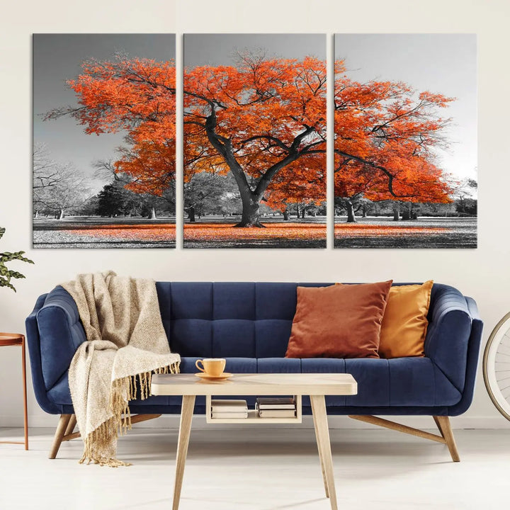 The "Orange Autumn Tree Canvas Wall Art Print" features a triptych of a tree with vibrant orange leaves set in a grayscale park. It's printed on museum-quality canvas and safeguarded by a UV-protective coating, making it the perfect artwork for any space.