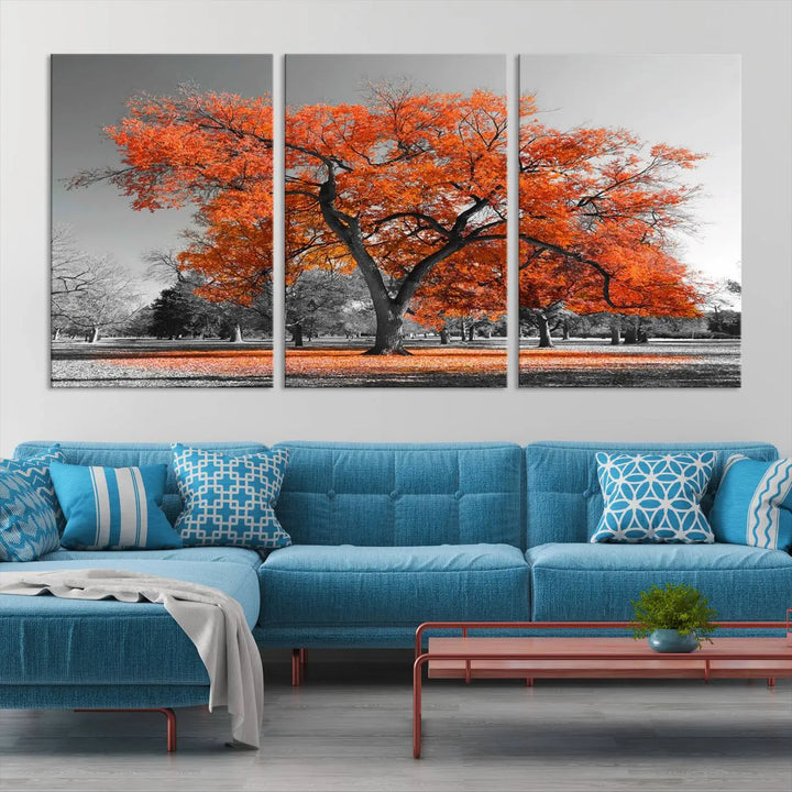 The "Orange Autumn Tree Canvas Wall Art Print" features a triptych of a tree with vibrant orange leaves set in a grayscale park. It's printed on museum-quality canvas and safeguarded by a UV-protective coating, making it the perfect artwork for any space.