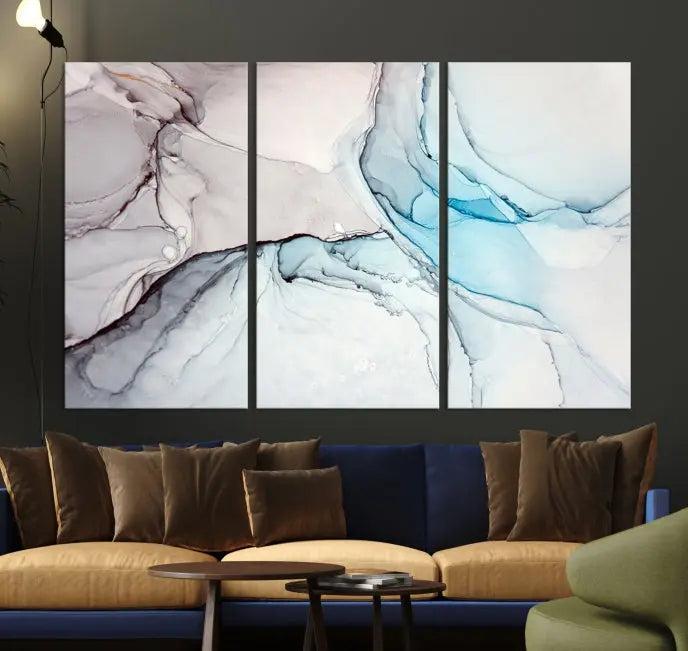 The "Pastel Marble Fluid Effect Wall Art Abstract Canvas Wall Art Print" elegantly enhances the area above a dark blue sofa. This art piece comes ready to hang.