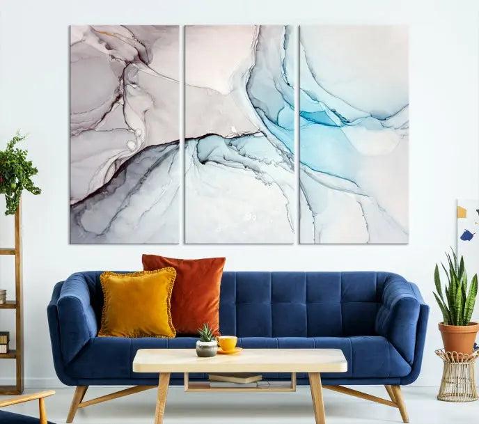 The "Pastel Marble Fluid Effect Wall Art Abstract Canvas Wall Art Print" elegantly enhances the area above a dark blue sofa. This art piece comes ready to hang.