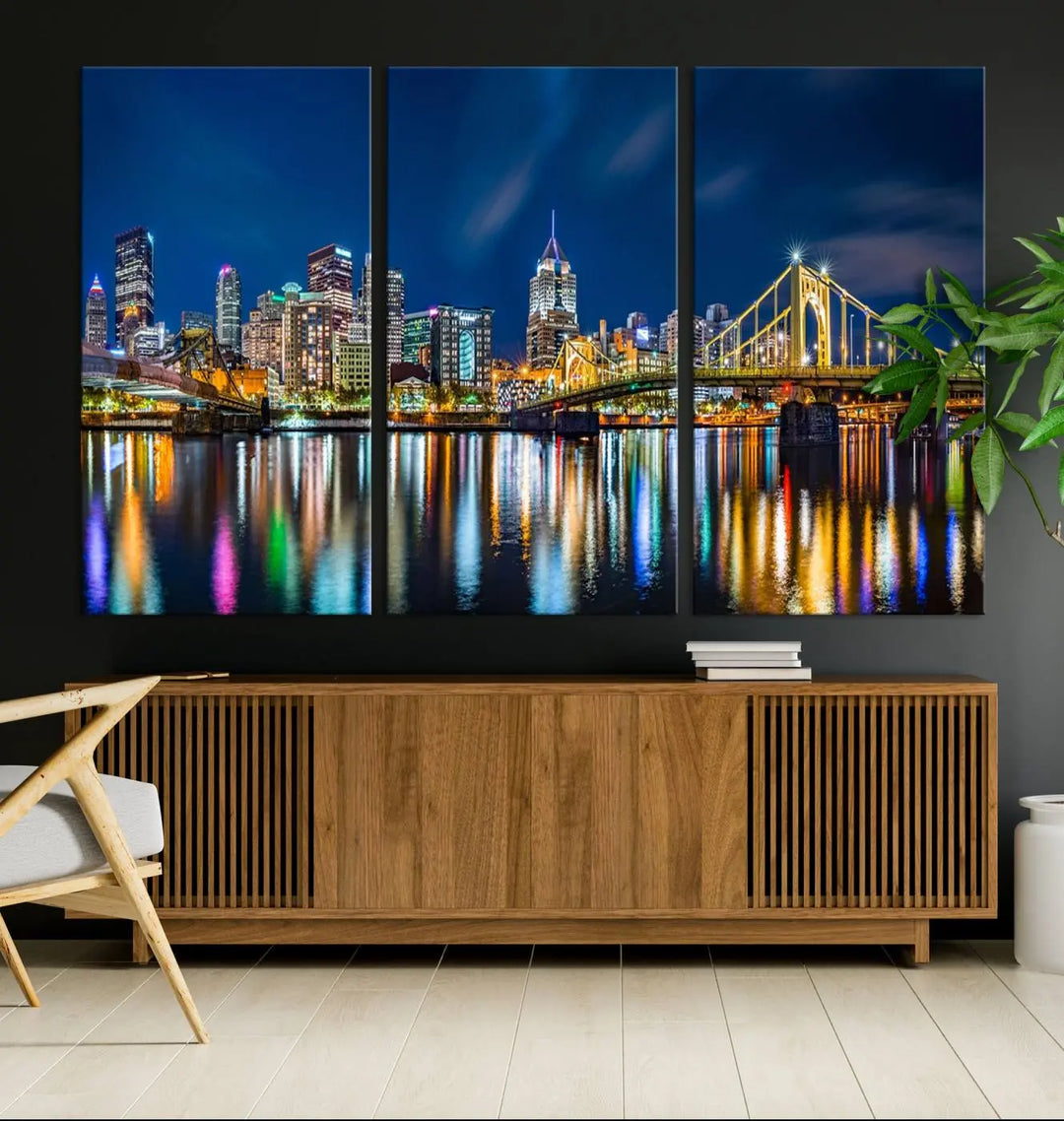 The living room features a gallery-wrapped triptych of Pittsburgh's skyline at night, reflecting on water. This Pittsburgh Skyline Canvas Wall Art is displayed above the cabinets and is printed on museum-quality canvas with a UV-protective coating to maintain its lasting vibrancy.