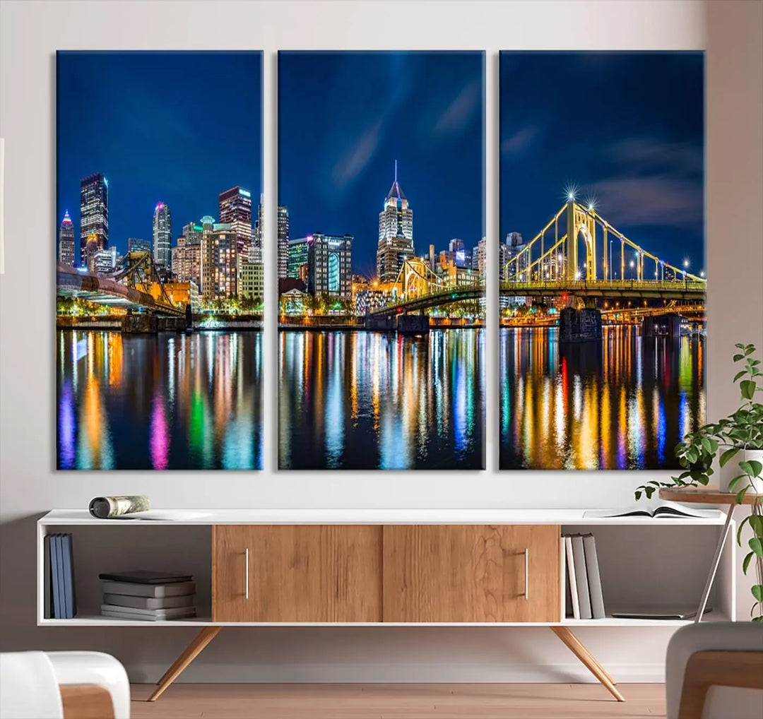 The living room features a gallery-wrapped triptych of Pittsburgh's skyline at night, reflecting on water. This Pittsburgh Skyline Canvas Wall Art is displayed above the cabinets and is printed on museum-quality canvas with a UV-protective coating to maintain its lasting vibrancy.