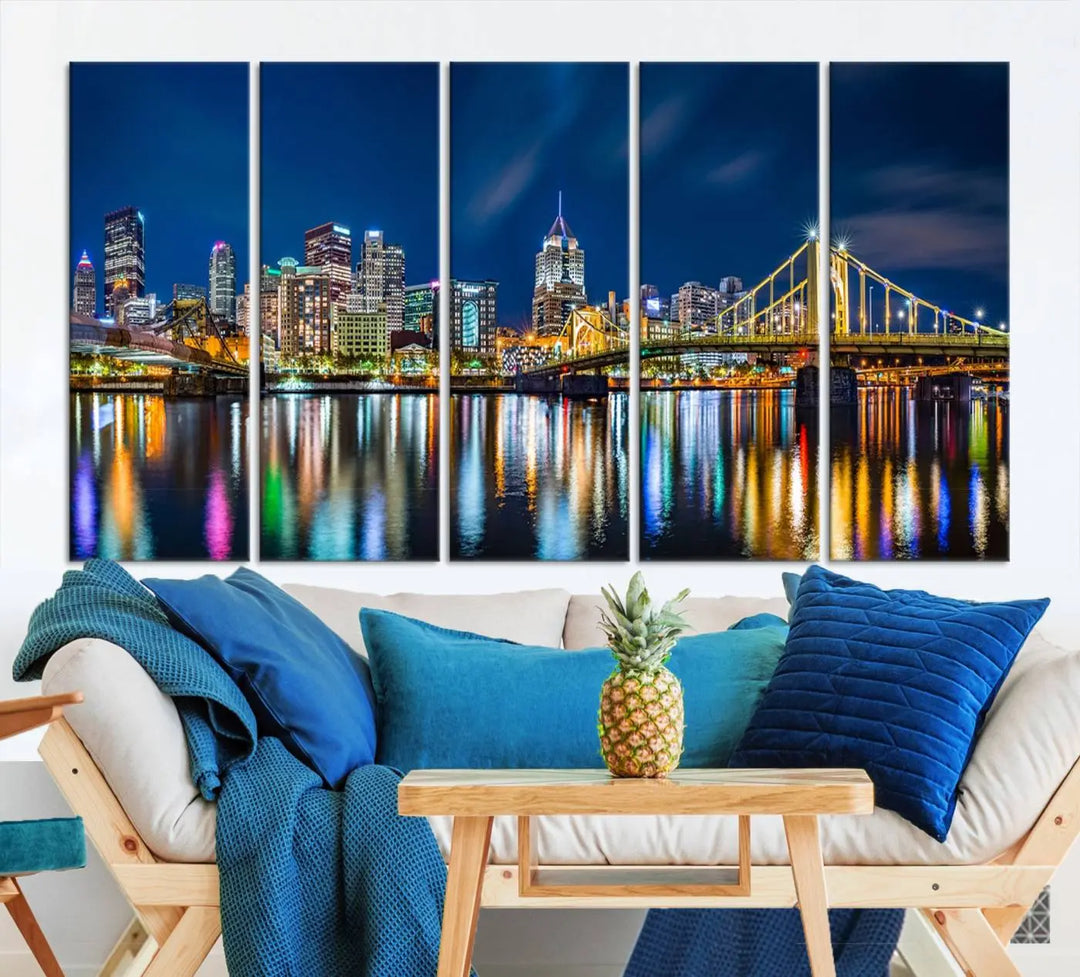 The living room features a gallery-wrapped triptych of Pittsburgh's skyline at night, reflecting on water. This Pittsburgh Skyline Canvas Wall Art is displayed above the cabinets and is printed on museum-quality canvas with a UV-protective coating to maintain its lasting vibrancy.