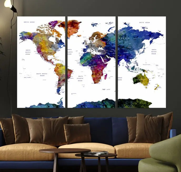 A modern living room is beautifully adorned with the Push Pin World Map Wall Art Canvas Print, a vibrant triptych of colorful world maps crafted on museum-quality canvas and perfectly gallery wrapped. This striking artwork stands out on its own, enhancing the room's overall aesthetics.