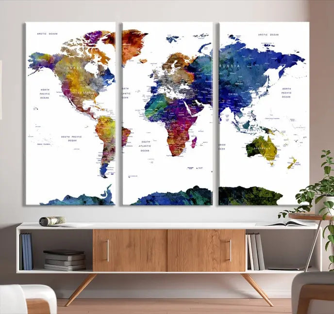 A modern living room is beautifully adorned with the Push Pin World Map Wall Art Canvas Print, a vibrant triptych of colorful world maps crafted on museum-quality canvas and perfectly gallery wrapped. This striking artwork stands out on its own, enhancing the room's overall aesthetics.