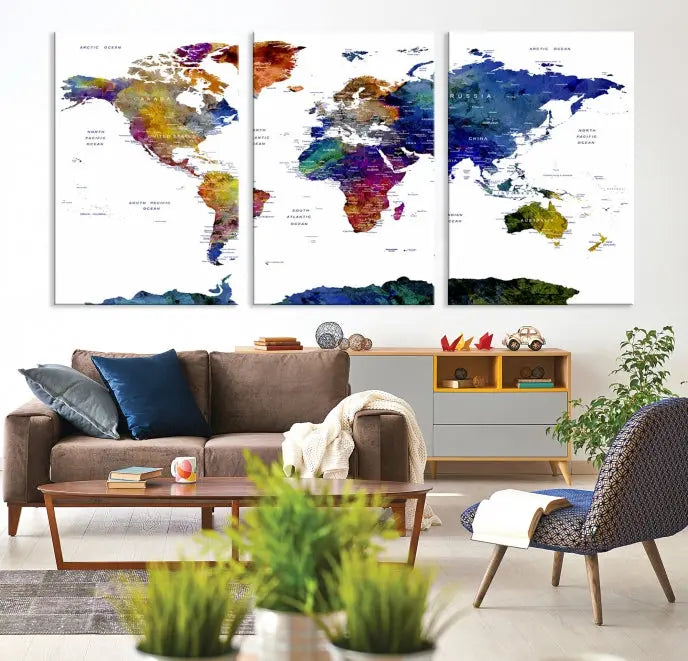 A modern living room is beautifully adorned with the Push Pin World Map Wall Art Canvas Print, a vibrant triptych of colorful world maps crafted on museum-quality canvas and perfectly gallery wrapped. This striking artwork stands out on its own, enhancing the room's overall aesthetics.