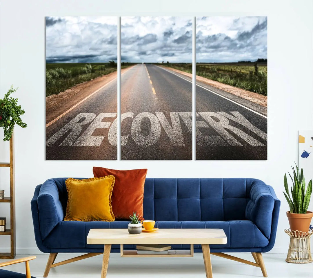 The Recovery Road Wall Art Canvas Print, a three-panel piece gallery wrapped on museum-quality canvas, displays an empty road with the word RECOVERY painted on it. This artwork is coated with UV-protection to maintain its vibrant colors over time.