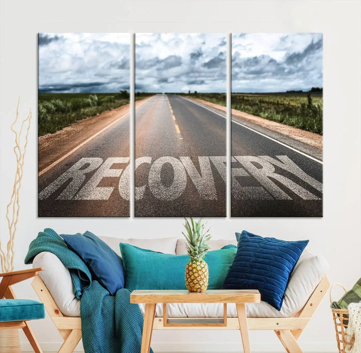 The Recovery Road Wall Art Canvas Print, a three-panel piece gallery wrapped on museum-quality canvas, displays an empty road with the word RECOVERY painted on it. This artwork is coated with UV-protection to maintain its vibrant colors over time.