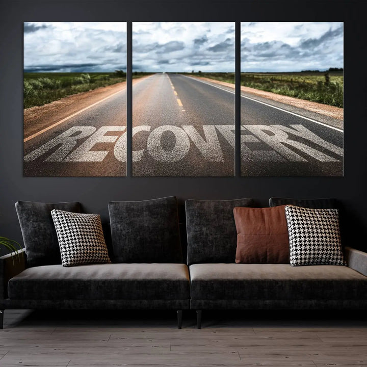 The Recovery Road Wall Art Canvas Print, a three-panel piece gallery wrapped on museum-quality canvas, displays an empty road with the word RECOVERY painted on it. This artwork is coated with UV-protection to maintain its vibrant colors over time.