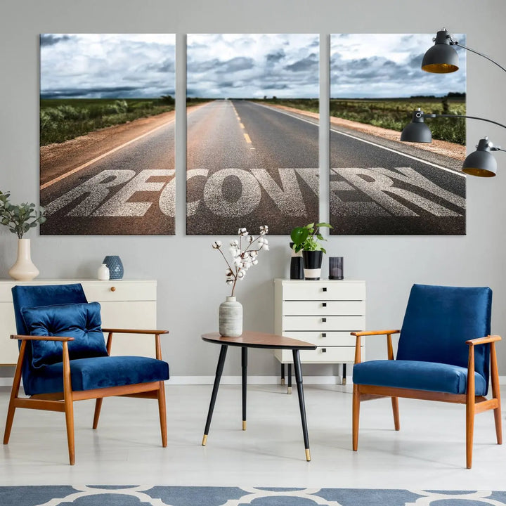 The Recovery Road Wall Art Canvas Print, a three-panel piece gallery wrapped on museum-quality canvas, displays an empty road with the word RECOVERY painted on it. This artwork is coated with UV-protection to maintain its vibrant colors over time.