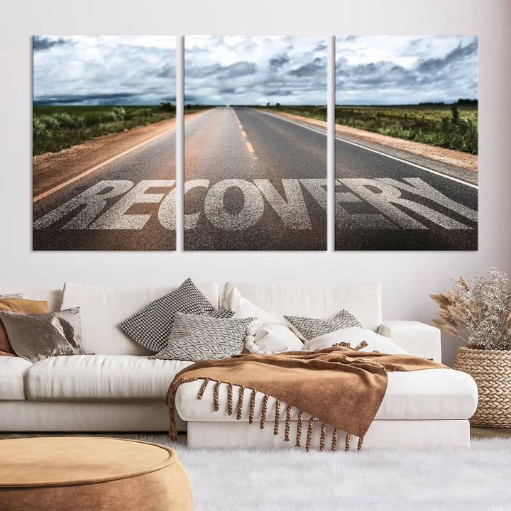 The Recovery Road Wall Art Canvas Print, a three-panel piece gallery wrapped on museum-quality canvas, displays an empty road with the word RECOVERY painted on it. This artwork is coated with UV-protection to maintain its vibrant colors over time.