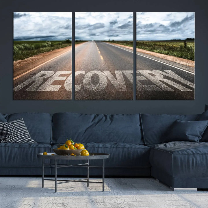 The Recovery Road Wall Art Canvas Print, a three-panel piece gallery wrapped on museum-quality canvas, displays an empty road with the word RECOVERY painted on it. This artwork is coated with UV-protection to maintain its vibrant colors over time.