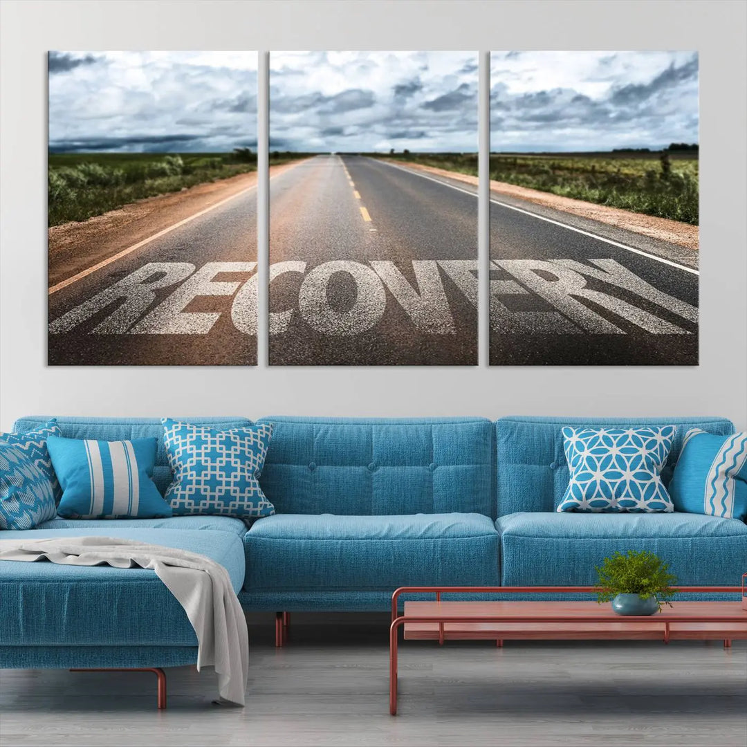 The Recovery Road Wall Art Canvas Print, a three-panel piece gallery wrapped on museum-quality canvas, displays an empty road with the word RECOVERY painted on it. This artwork is coated with UV-protection to maintain its vibrant colors over time.