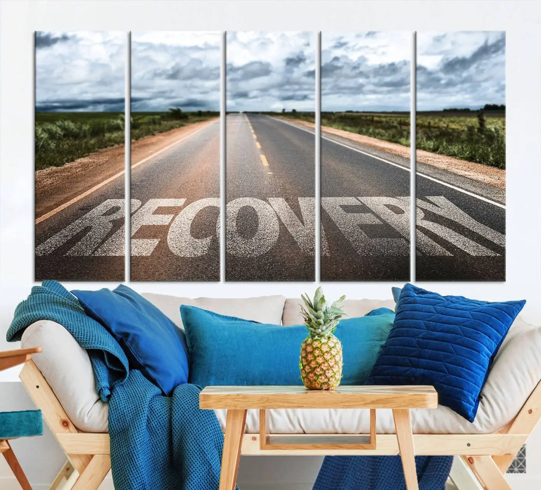 The Recovery Road Wall Art Canvas Print, a three-panel piece gallery wrapped on museum-quality canvas, displays an empty road with the word RECOVERY painted on it. This artwork is coated with UV-protection to maintain its vibrant colors over time.