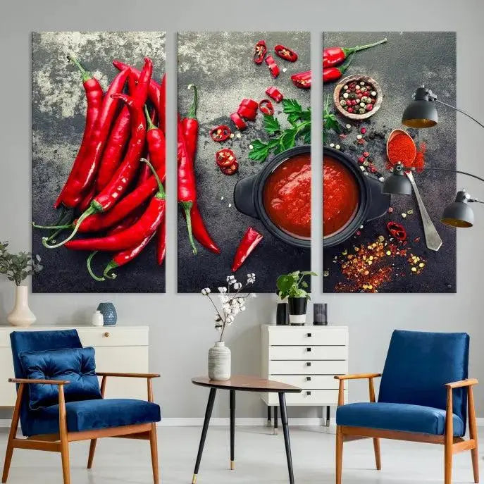 The Red Chili Peppers Wall Art Kitchen Artwork Canvas Print is a three-panel canvas showcasing red chili peppers, sliced chili, a pot of red sauce, and assorted spices on a dark background. It is of museum quality with a UV-protective coating to ensure its colors remain vibrant over time.