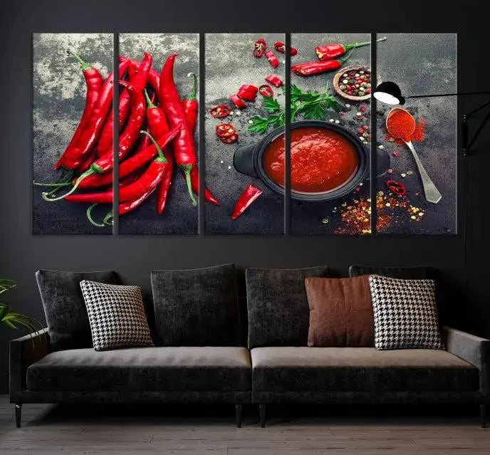 The Red Chili Peppers Wall Art Kitchen Artwork Canvas Print is a three-panel canvas showcasing red chili peppers, sliced chili, a pot of red sauce, and assorted spices on a dark background. It is of museum quality with a UV-protective coating to ensure its colors remain vibrant over time.