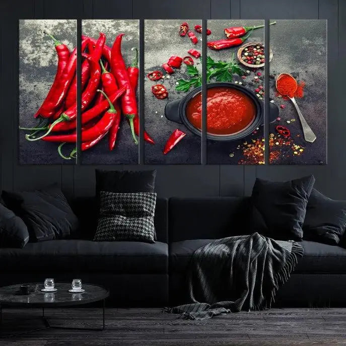 The Red Chili Peppers Wall Art Kitchen Artwork Canvas Print is a three-panel canvas showcasing red chili peppers, sliced chili, a pot of red sauce, and assorted spices on a dark background. It is of museum quality with a UV-protective coating to ensure its colors remain vibrant over time.