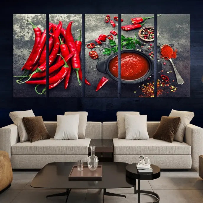 The Red Chili Peppers Wall Art Kitchen Artwork Canvas Print is a three-panel canvas showcasing red chili peppers, sliced chili, a pot of red sauce, and assorted spices on a dark background. It is of museum quality with a UV-protective coating to ensure its colors remain vibrant over time.