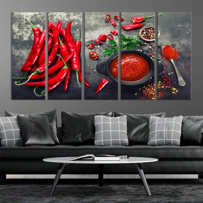 The Red Chili Peppers Wall Art Kitchen Artwork Canvas Print is a three-panel canvas showcasing red chili peppers, sliced chili, a pot of red sauce, and assorted spices on a dark background. It is of museum quality with a UV-protective coating to ensure its colors remain vibrant over time.