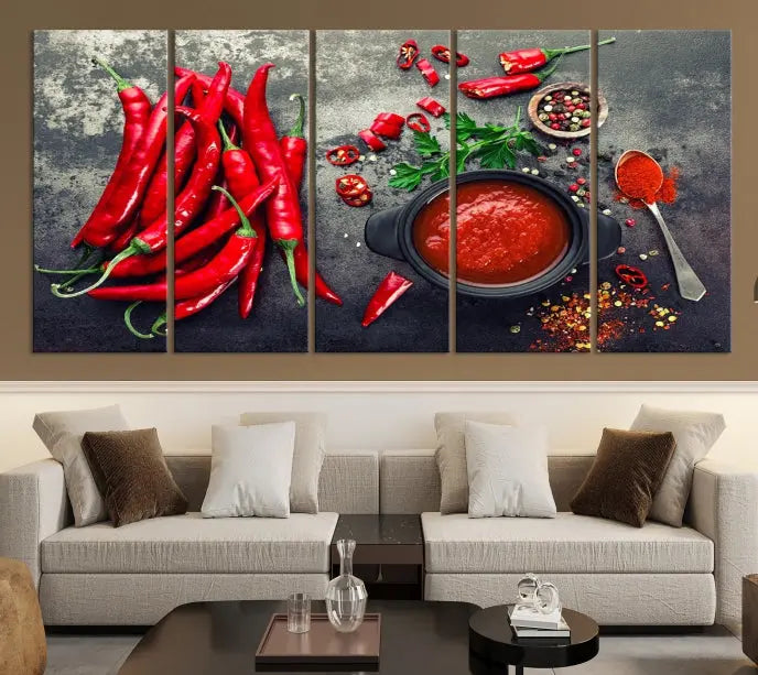 The Red Chili Peppers Wall Art Kitchen Artwork Canvas Print is a three-panel canvas showcasing red chili peppers, sliced chili, a pot of red sauce, and assorted spices on a dark background. It is of museum quality with a UV-protective coating to ensure its colors remain vibrant over time.