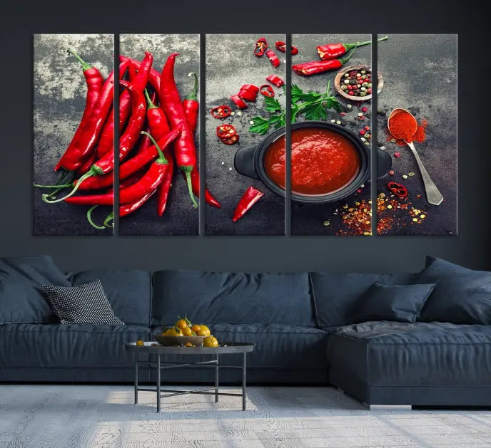 The Red Chili Peppers Wall Art Kitchen Artwork Canvas Print is a three-panel canvas showcasing red chili peppers, sliced chili, a pot of red sauce, and assorted spices on a dark background. It is of museum quality with a UV-protective coating to ensure its colors remain vibrant over time.