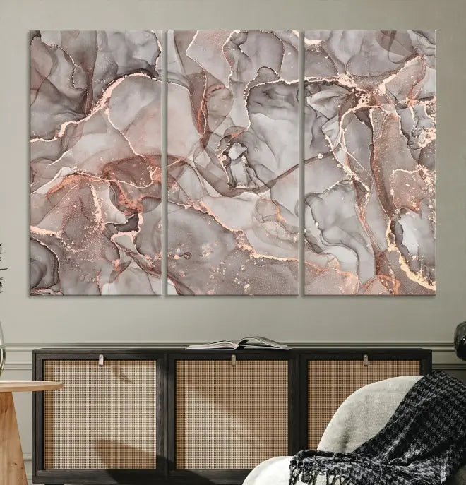 The Rose Gold Marble Fluid Effect Wall Art Abstract Canvas Wall Art Print is an exquisite three-panel creation crafted on museum-quality canvas. It features swirling marbled patterns in shades of gray, copper, and beige. Complete with a UV-protective coating, this ready-to-hang artwork promises to be a timeless addition to any space.