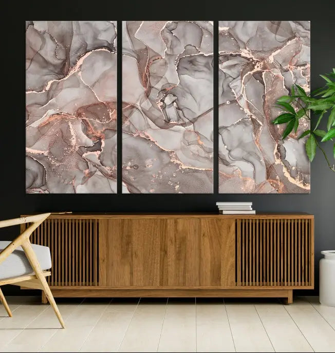 The Rose Gold Marble Fluid Effect Wall Art Abstract Canvas Wall Art Print is an exquisite three-panel creation crafted on museum-quality canvas. It features swirling marbled patterns in shades of gray, copper, and beige. Complete with a UV-protective coating, this ready-to-hang artwork promises to be a timeless addition to any space.