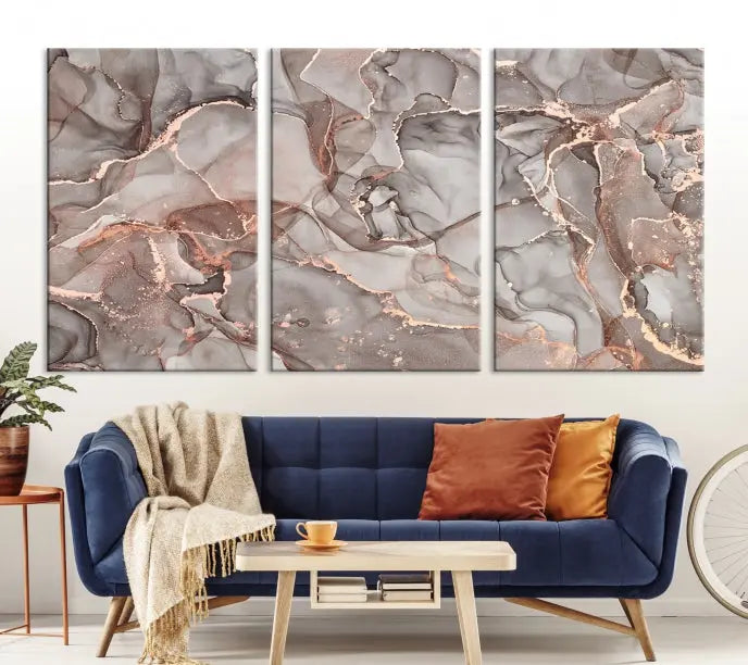 The Rose Gold Marble Fluid Effect Wall Art Abstract Canvas Wall Art Print is an exquisite three-panel creation crafted on museum-quality canvas. It features swirling marbled patterns in shades of gray, copper, and beige. Complete with a UV-protective coating, this ready-to-hang artwork promises to be a timeless addition to any space.