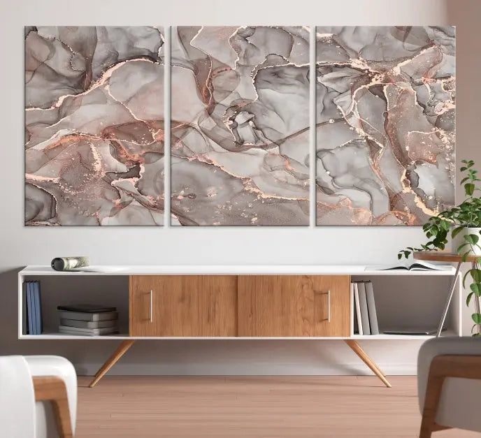 The Rose Gold Marble Fluid Effect Wall Art Abstract Canvas Wall Art Print is an exquisite three-panel creation crafted on museum-quality canvas. It features swirling marbled patterns in shades of gray, copper, and beige. Complete with a UV-protective coating, this ready-to-hang artwork promises to be a timeless addition to any space.