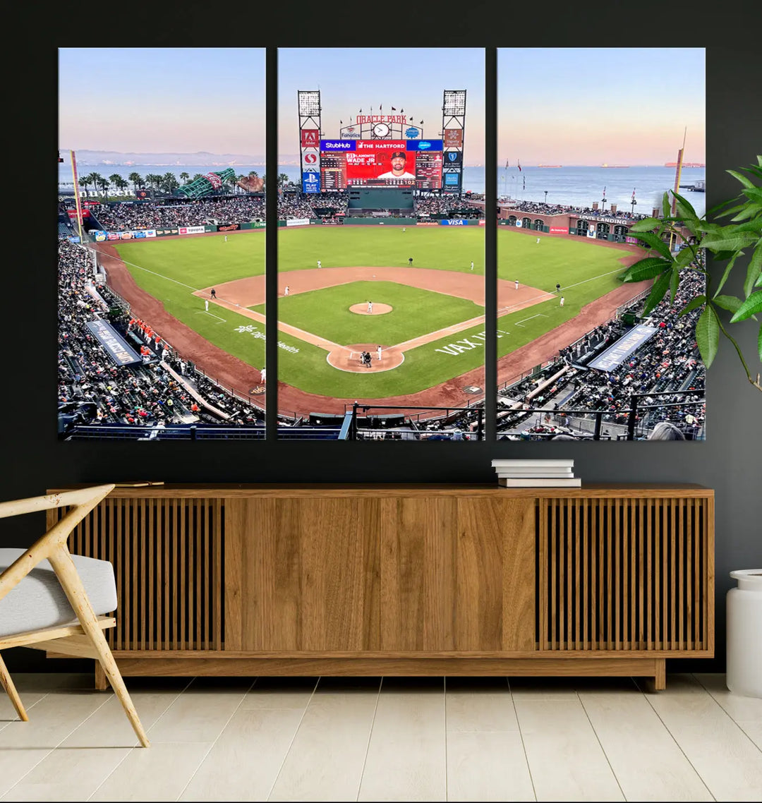 A San Francisco Giants Baseball Team Print featuring Oracle Park Stadium, a triptych canvas wall art handmade in the USA, hangs prominently in a modern room.