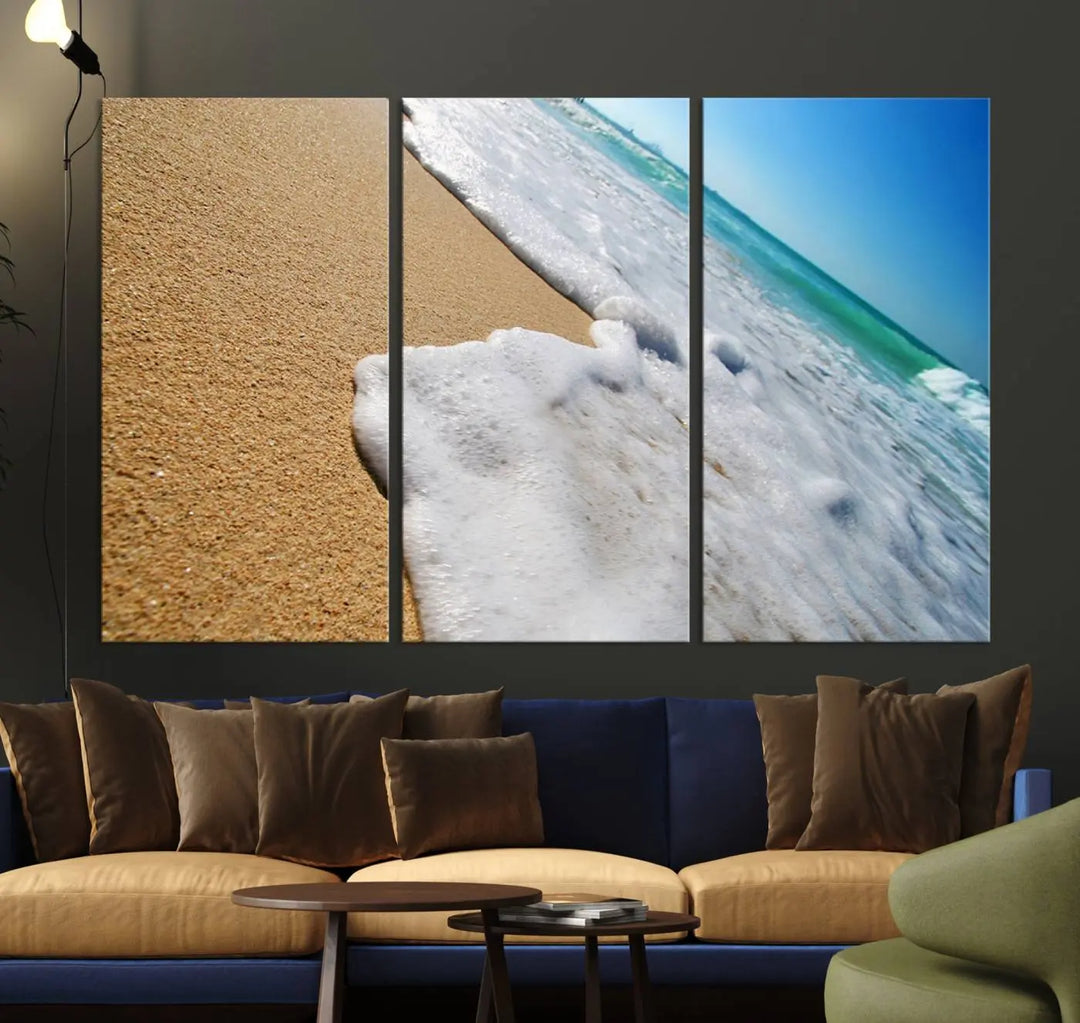 The Sandy Shoreline Close-Up Ocean Wave Canvas Print, depicting waves washing onto the sand, adorns the wall.