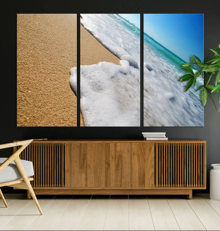 The Sandy Shoreline Close-Up Ocean Wave Canvas Print, depicting waves washing onto the sand, adorns the wall.