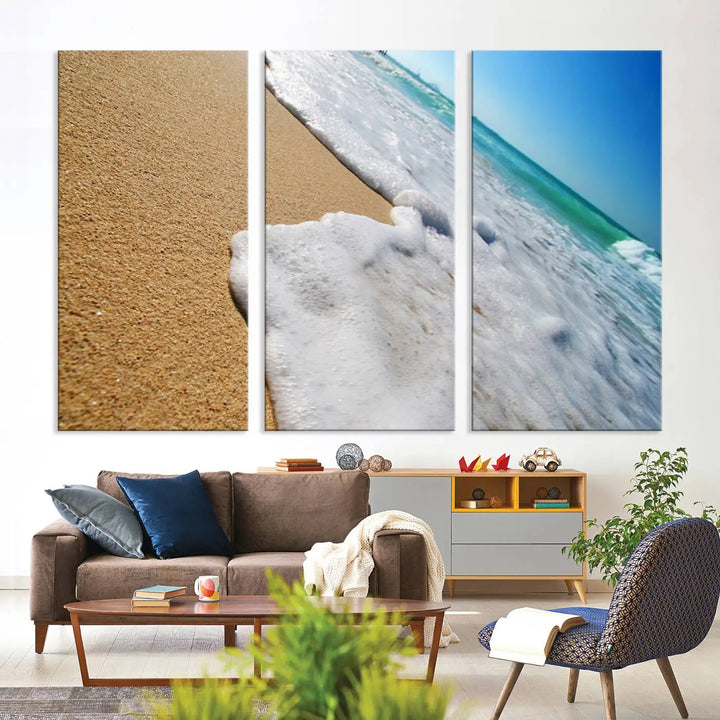 The Sandy Shoreline Close-Up Ocean Wave Canvas Print, depicting waves washing onto the sand, adorns the wall.