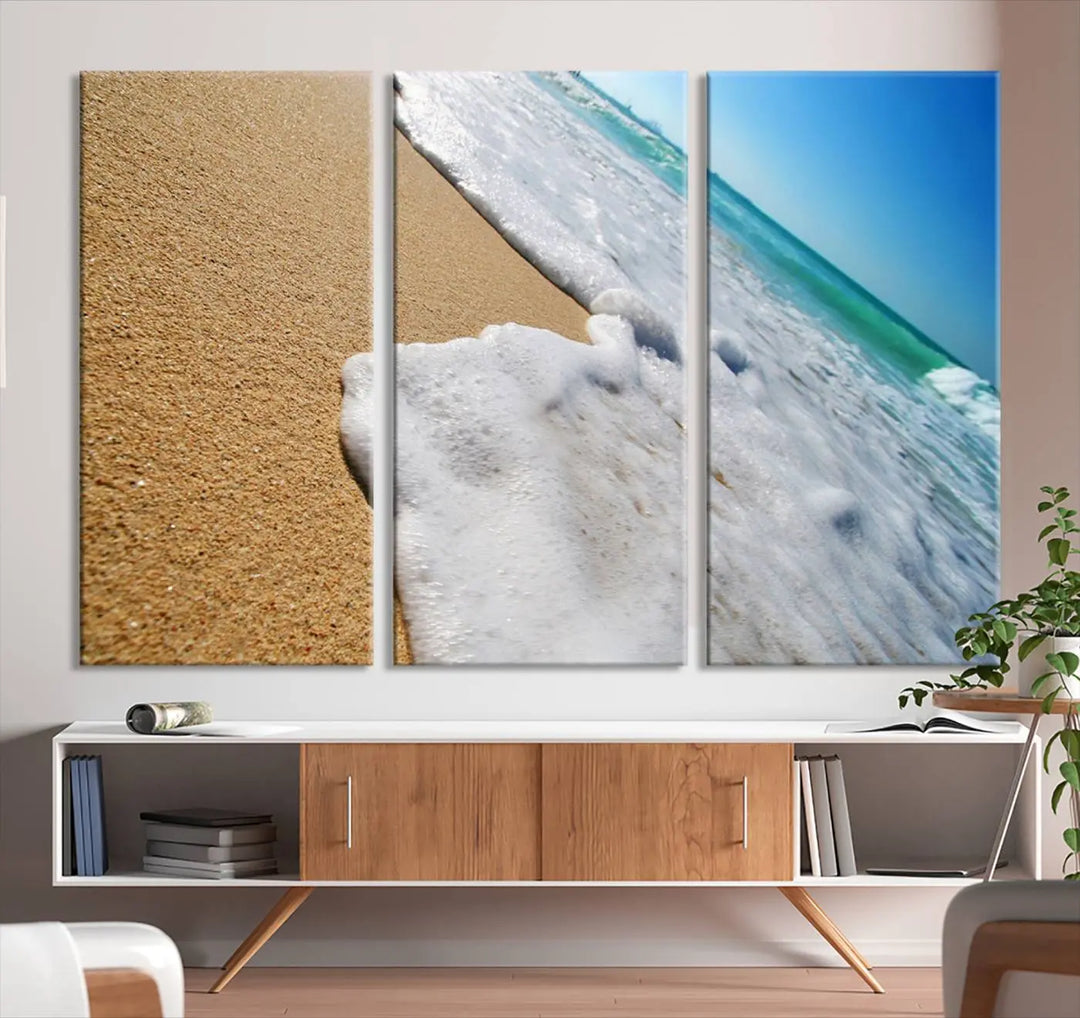 The Sandy Shoreline Close-Up Ocean Wave Canvas Print, depicting waves washing onto the sand, adorns the wall.