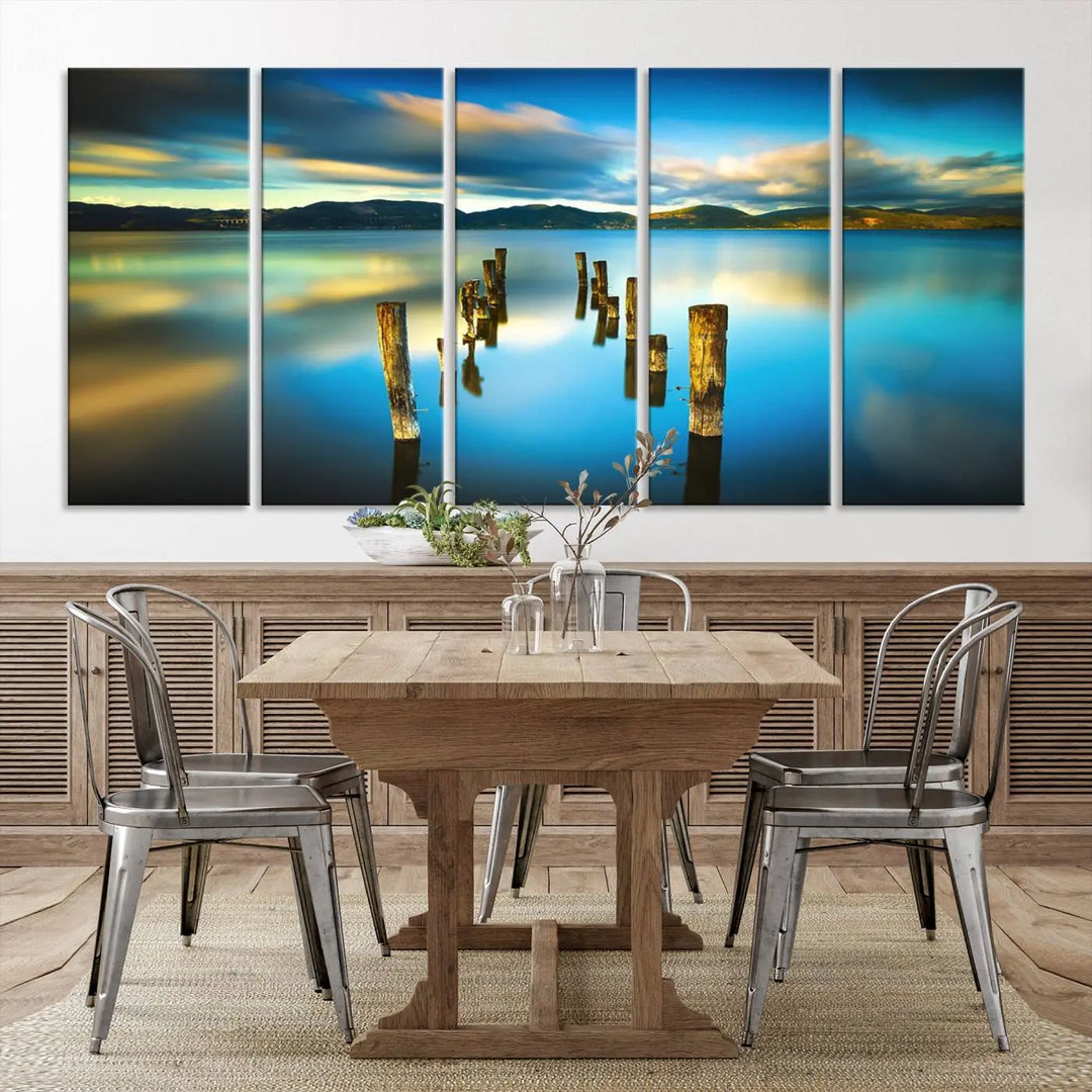 A triptych of a serene lake scene with old wooden pillars, blue sky, and clouds casts a coastal ambiance. The Sea Ocean Sunset Beach Wall Art Canvas Print reflects the soothing nature of the ocean.