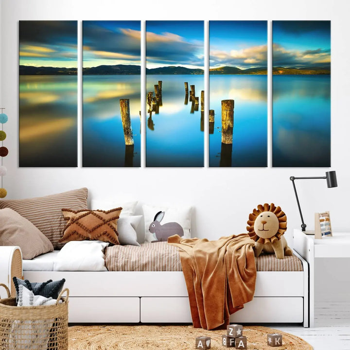 A triptych of a serene lake scene with old wooden pillars, blue sky, and clouds casts a coastal ambiance. The Sea Ocean Sunset Beach Wall Art Canvas Print reflects the soothing nature of the ocean.