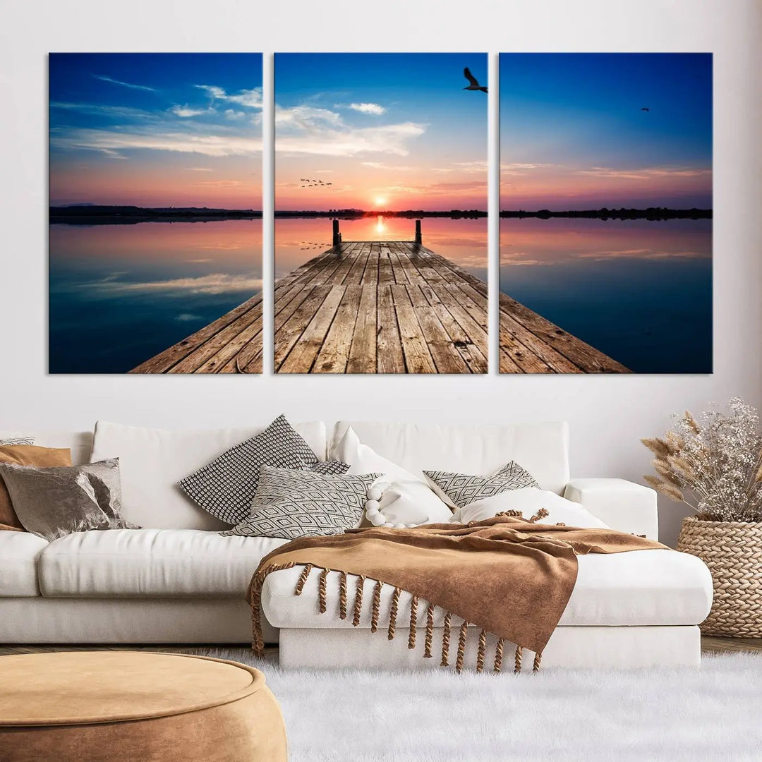 A Sea Wooden Pier Canvas Wall Art, featuring a sunset artwork print of the beach, fosters a coastal ambiance in the modern living room.