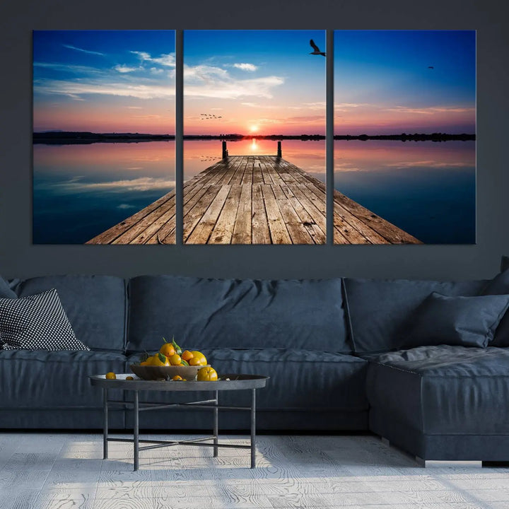 A Sea Wooden Pier Canvas Wall Art, featuring a sunset artwork print of the beach, fosters a coastal ambiance in the modern living room.