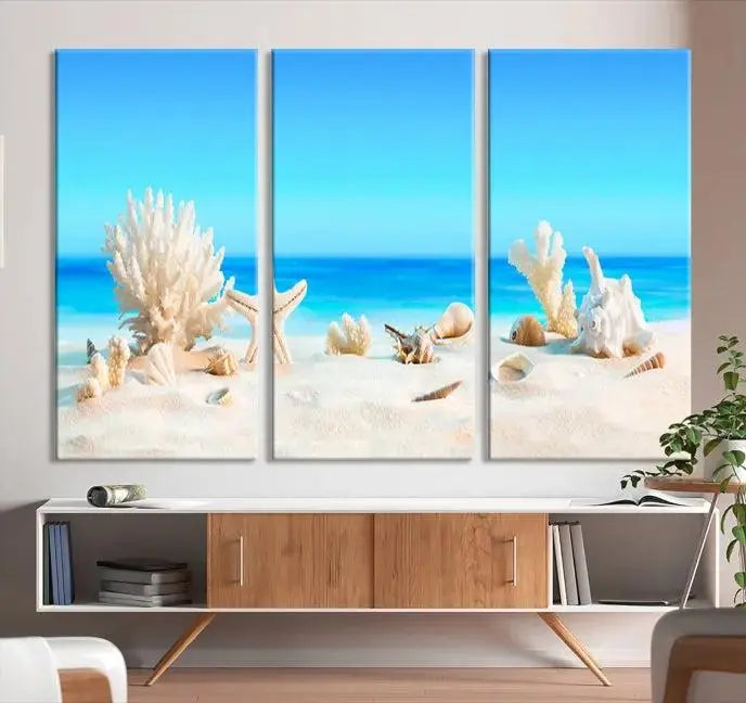 The Seashell Wall Art Canvas Print features a triptych of a beach scene, complete with coral, starfish, and seashells on sand. Printed on museum-quality canvas with UV-protective coating, it is ready to hang and brings vibrant charm to any living room.