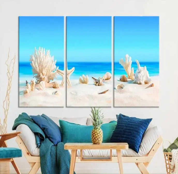 The Seashell Wall Art Canvas Print features a triptych of a beach scene, complete with coral, starfish, and seashells on sand. Printed on museum-quality canvas with UV-protective coating, it is ready to hang and brings vibrant charm to any living room.