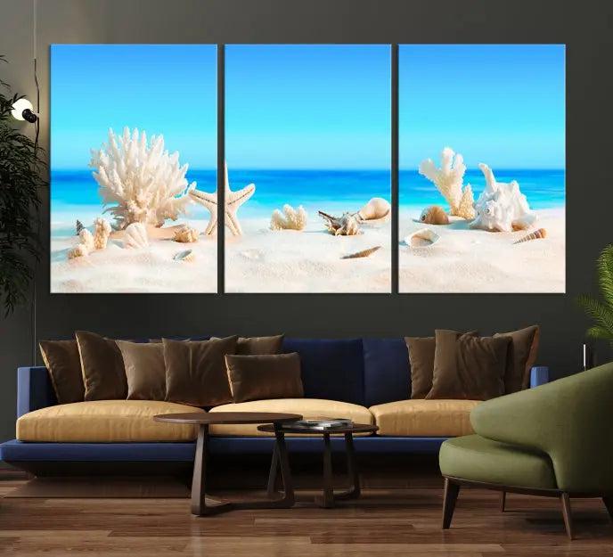 The Seashell Wall Art Canvas Print features a triptych of a beach scene, complete with coral, starfish, and seashells on sand. Printed on museum-quality canvas with UV-protective coating, it is ready to hang and brings vibrant charm to any living room.