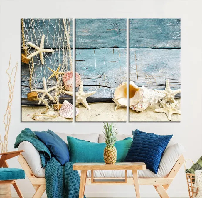 The beautiful three-panel canvas print, "Seashells on Rustic Wooden Background," features seashells and starfish against a blue wood background. The gallery-wrapped panels are coated with UV protection to ensure long-lasting vibrancy.