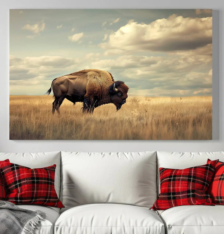 The Sepia American Bison Wall Art Print, a Western canvas print, depicts a bison standing in a grassy field beneath a cloudy sky. This high-resolution museum-quality triptych wall art is ideal for farmhouse wall decor.